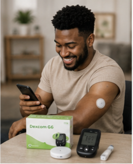 Man smiling at a phone beside a Dexcom G6 glucose monitor and sensor kit on a table