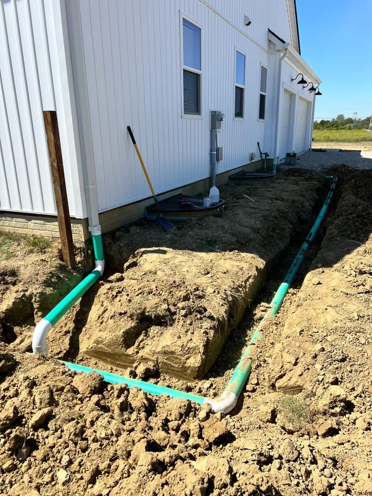 A white house with a lot of dirt and pipes in front of it.