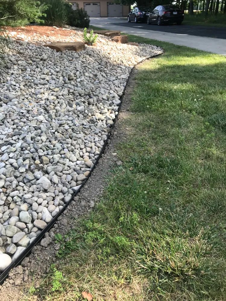 A lawn with a gravel border and a car parked on the side of the road.