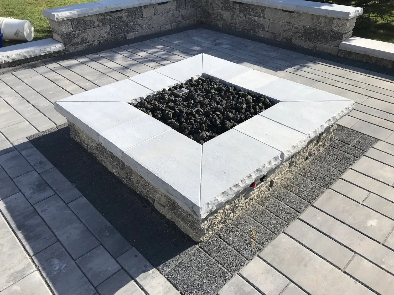 A square fire pit sitting on top of a brick patio