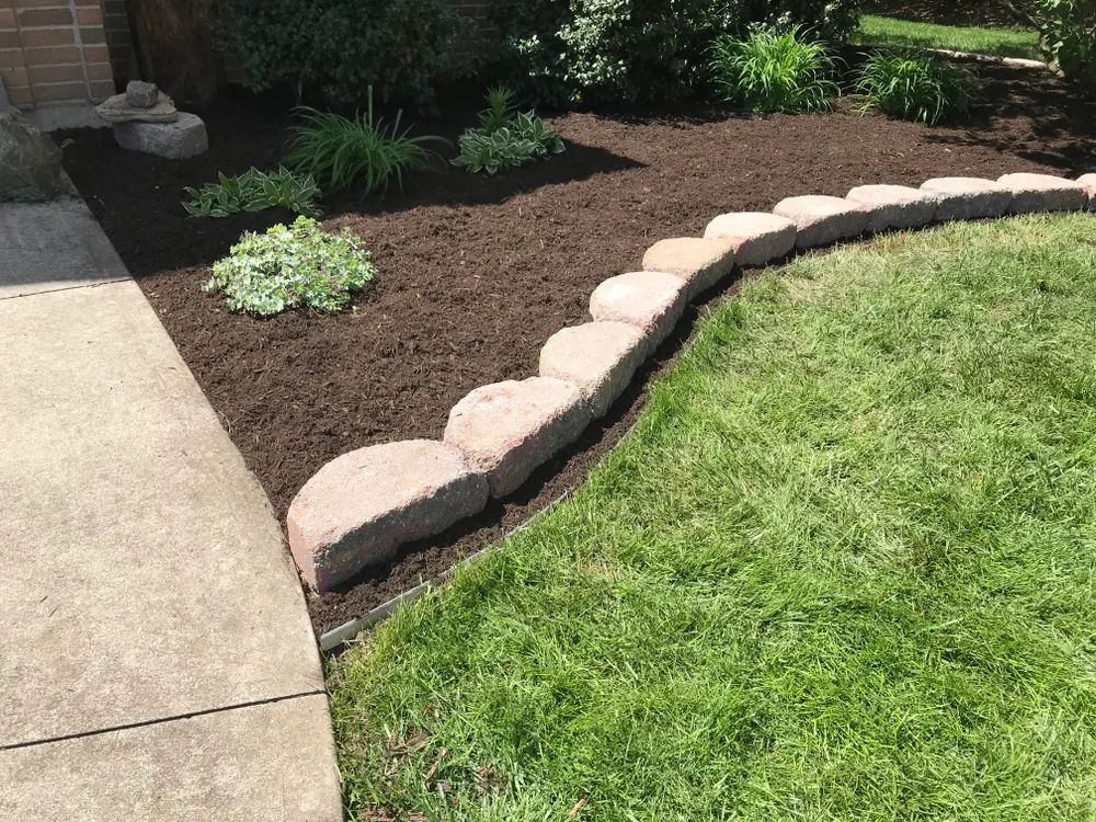 A lawn with a stone border and a brick walkway.
