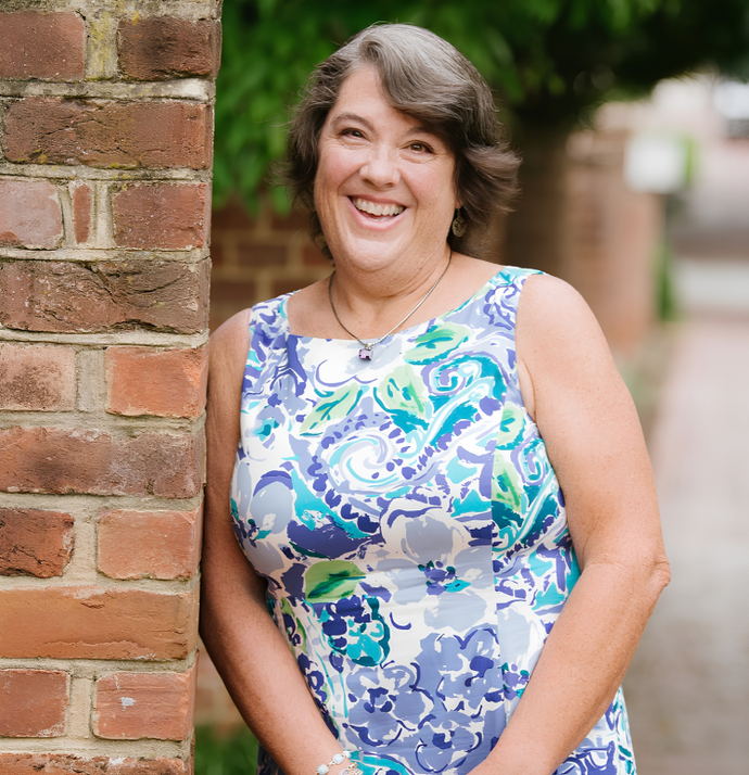 A woman in a purple shirt is smiling for the camera