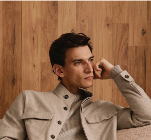 A man is sitting on a couch with his hand on his face.