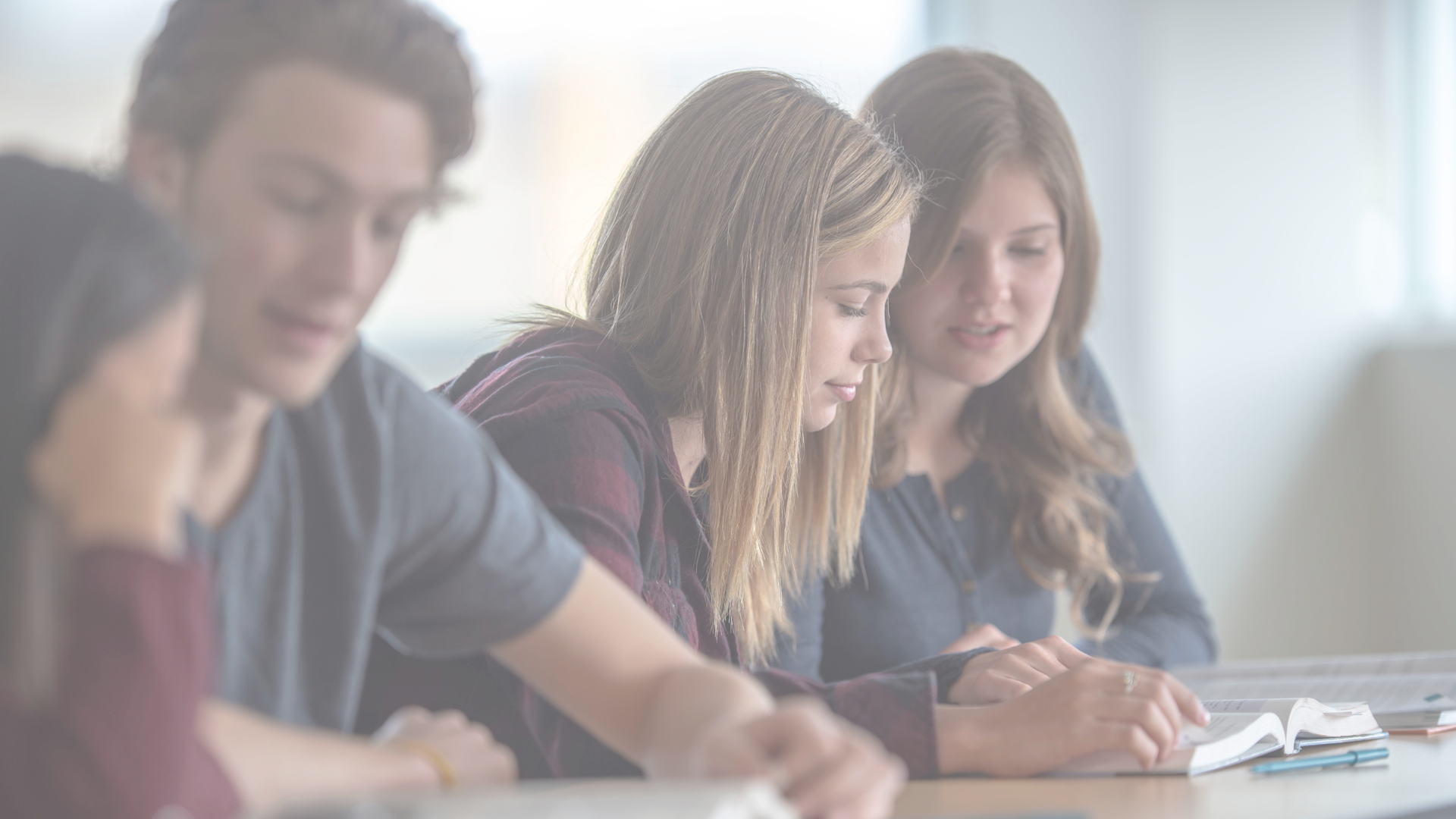 um grupo de jovens está sentado à mesa de uma sala de aula.