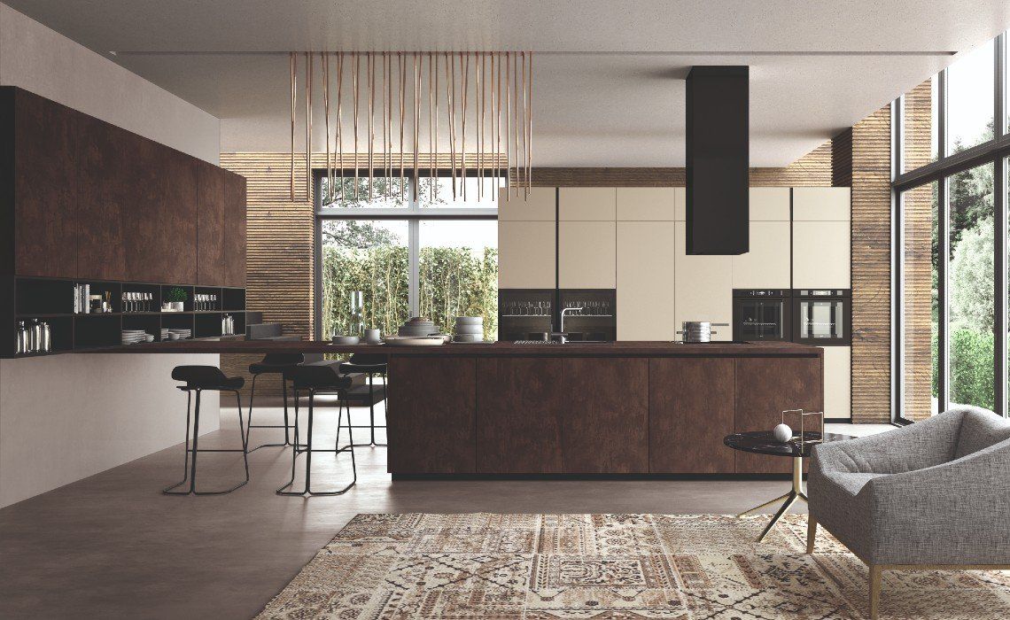 Cucina moderna con una lunga isola marrone, sgabelli da bar, mobili chiari, una lampada a sospensione e una poltrona.