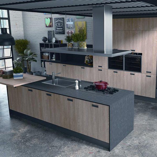 Una cucina moderna con isola grigio scuro con finitura effetto legno, piano cottura integrato e lavello sotto cappa metallica.