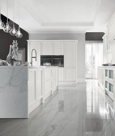 Cucina moderna con isola centrale con piano in marmo, mobili bianchi in stile shaker, pareti grigie e grandi piastrelle a pavimento.