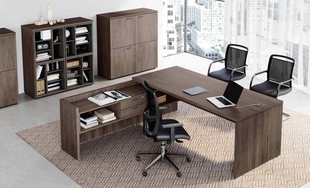 Un ufficio moderno con scrivania direzionale in legno, tre sedie in rete nera, scaffali e armadietti, il tutto su un tappeto a motivi geometrici.