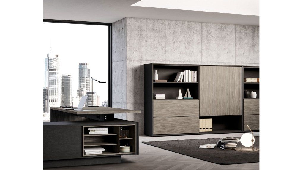 Un moderno ufficio direzionale caratterizzato da un'elegante scrivania scura con ripiani integrati e un grande mobile a parete coordinato.