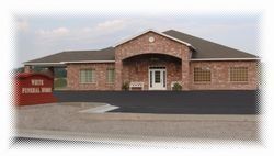 Brick funeral home building with red sign and black asphalt parking lot