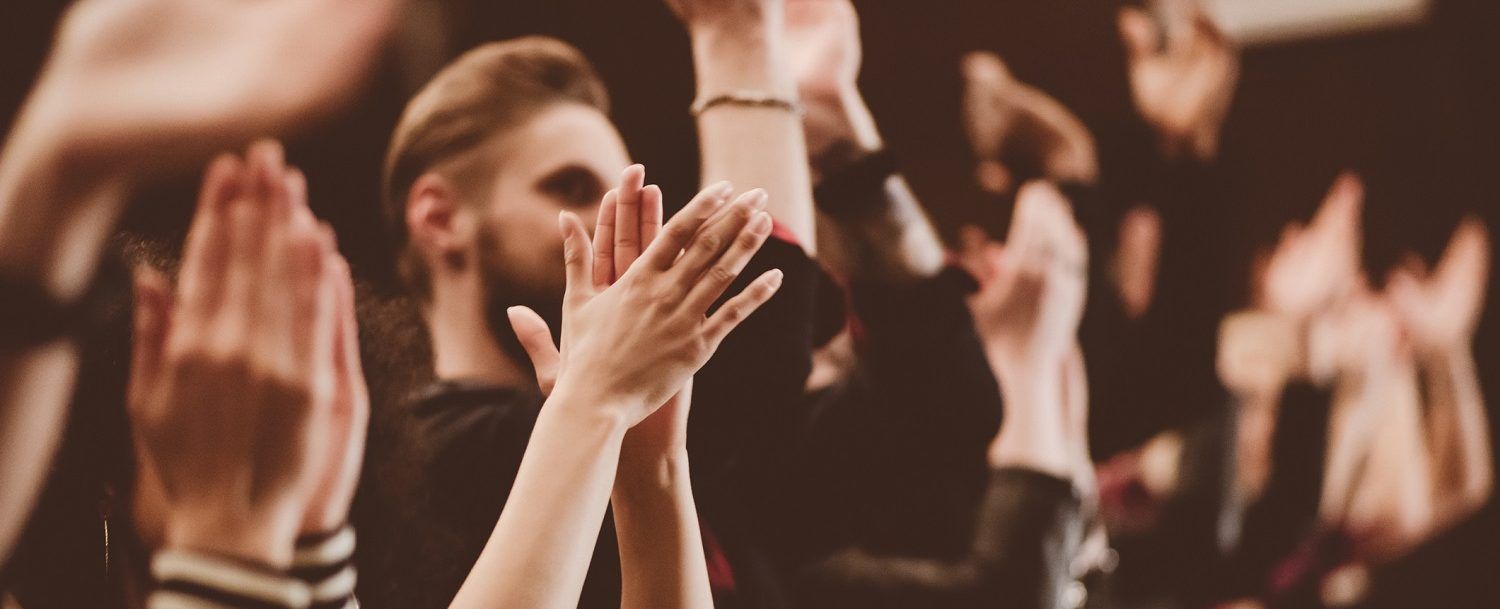 a crowd of people are clapping their hands in the air at a concert .