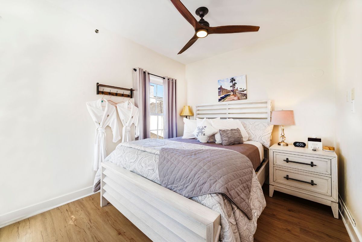 a bedroom with a bed , nightstand , dresser and ceiling fan .