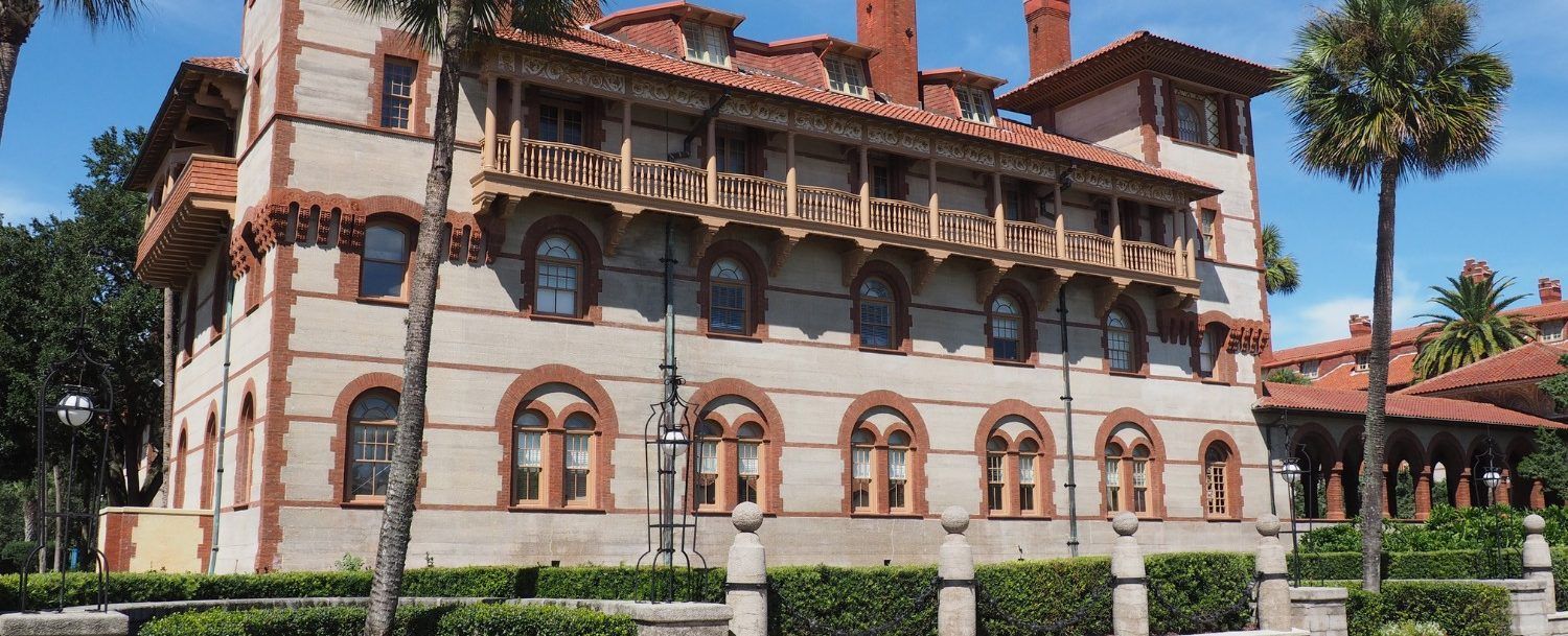 a large building with a red tile roof is surrounded by palm trees .