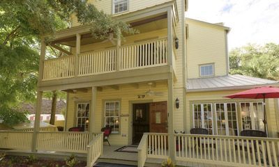 a large yellow house with a large porch and a red umbrella .