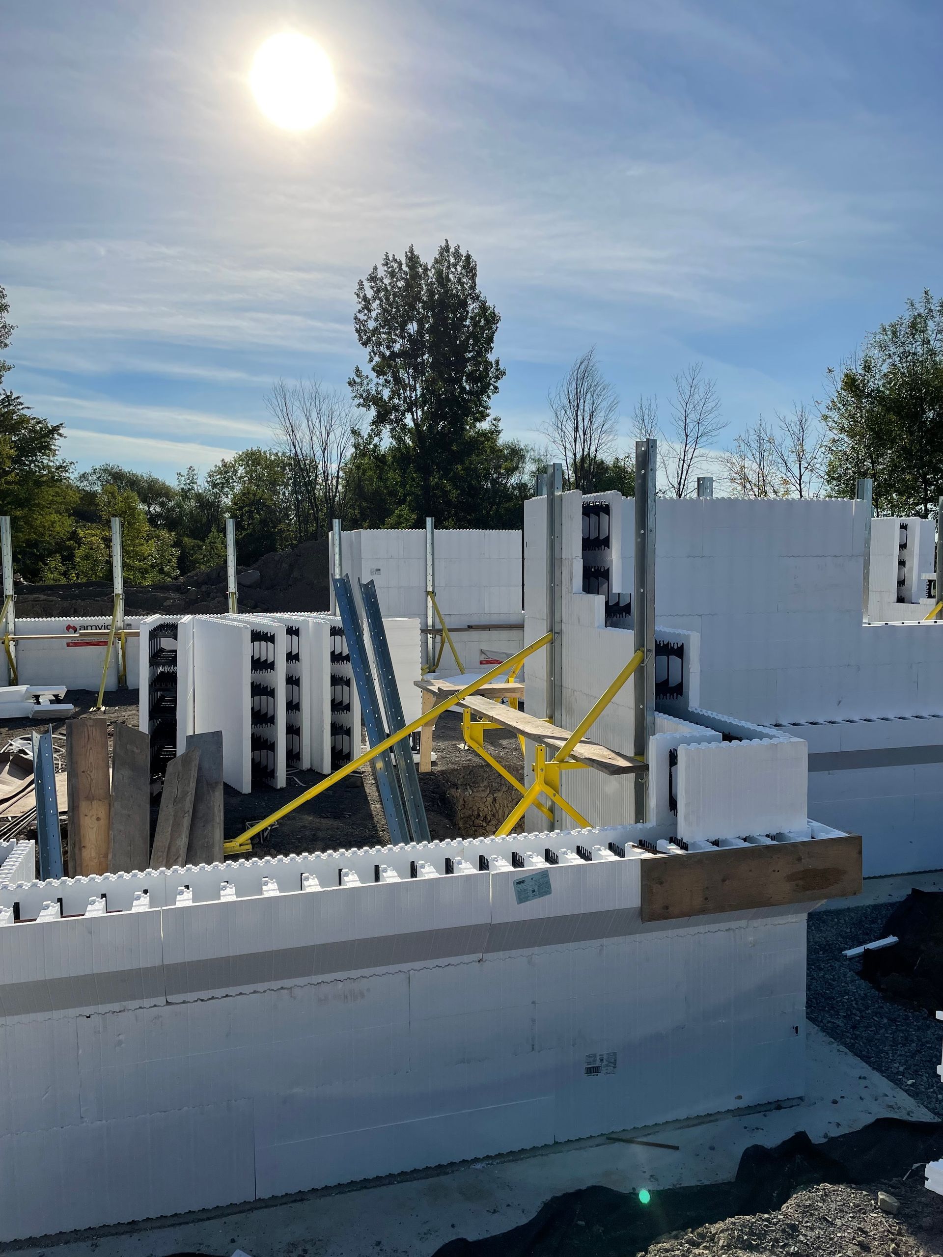 Chantier de construction avec blocs de mousse blanche, échafaudages et lumière du soleil.