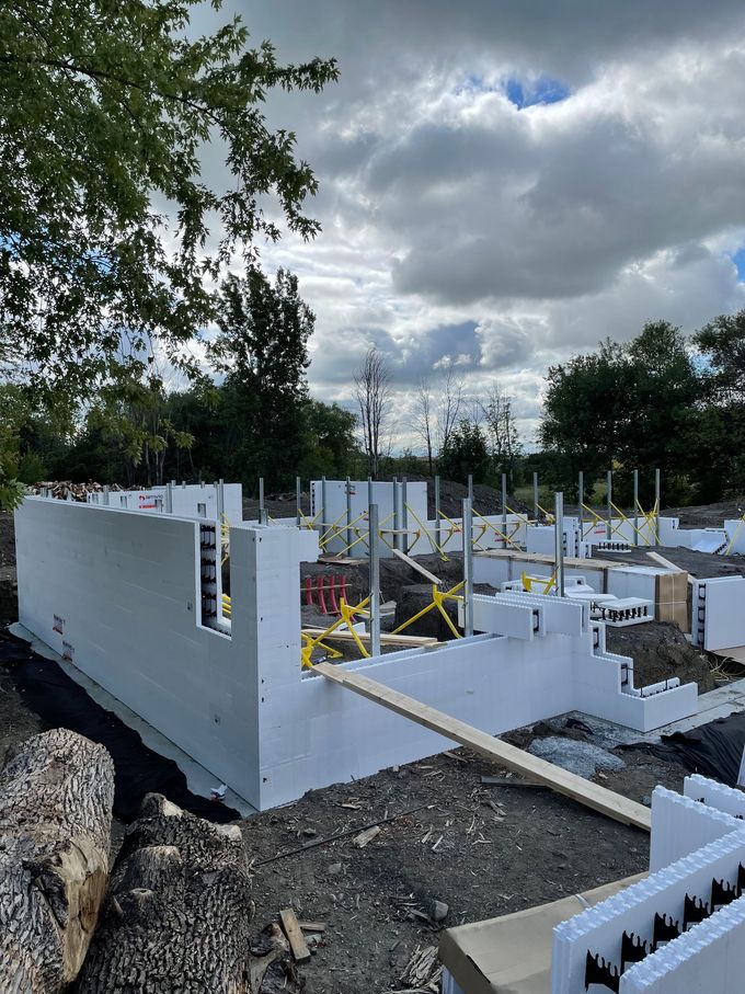Fondations d'un bâtiment en construction, réalisées à l'aide de coffrages isolants en béton ; ciel nuageux en arrière-plan.