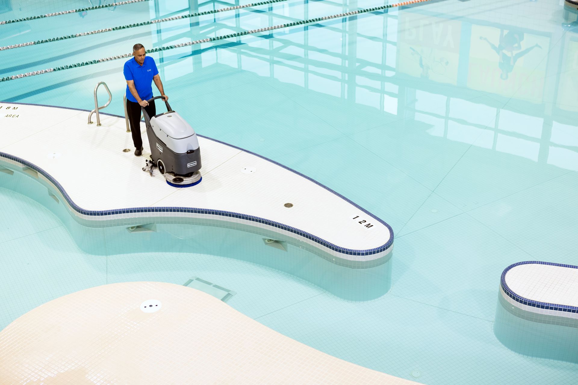 A man is cleaning a swimming pool with a machine.