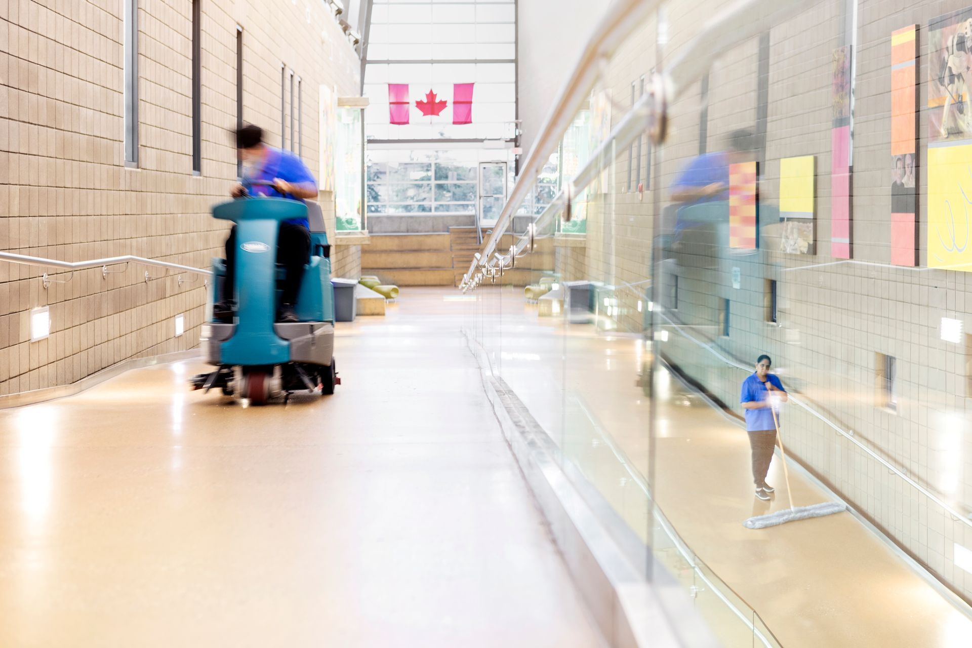 A man is riding a cleaning machine down a hallway.