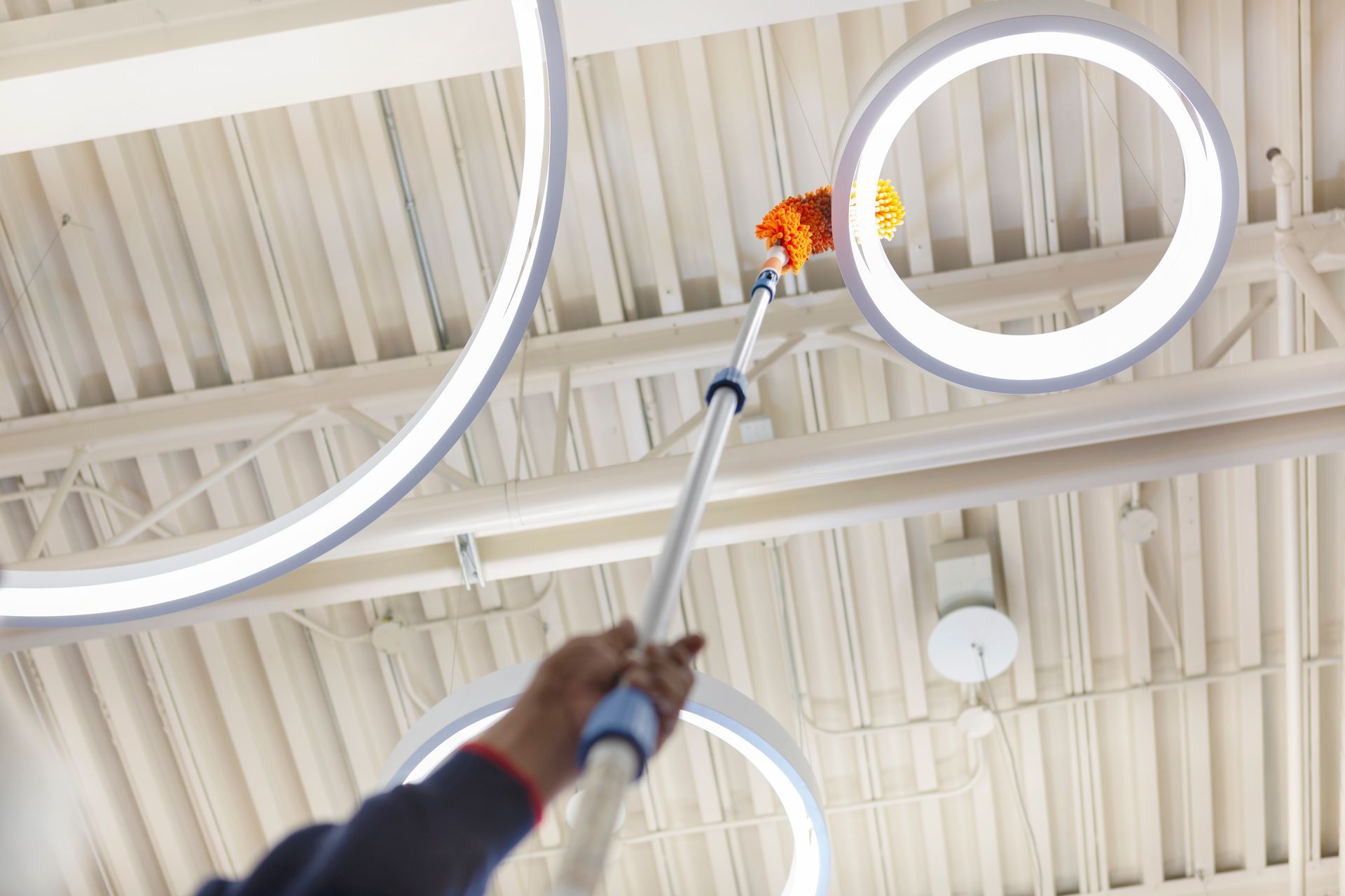 A person is cleaning the ceiling of a building with a broom.
