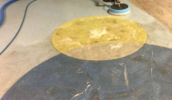 A blue and yellow rug is being cleaned by a machine