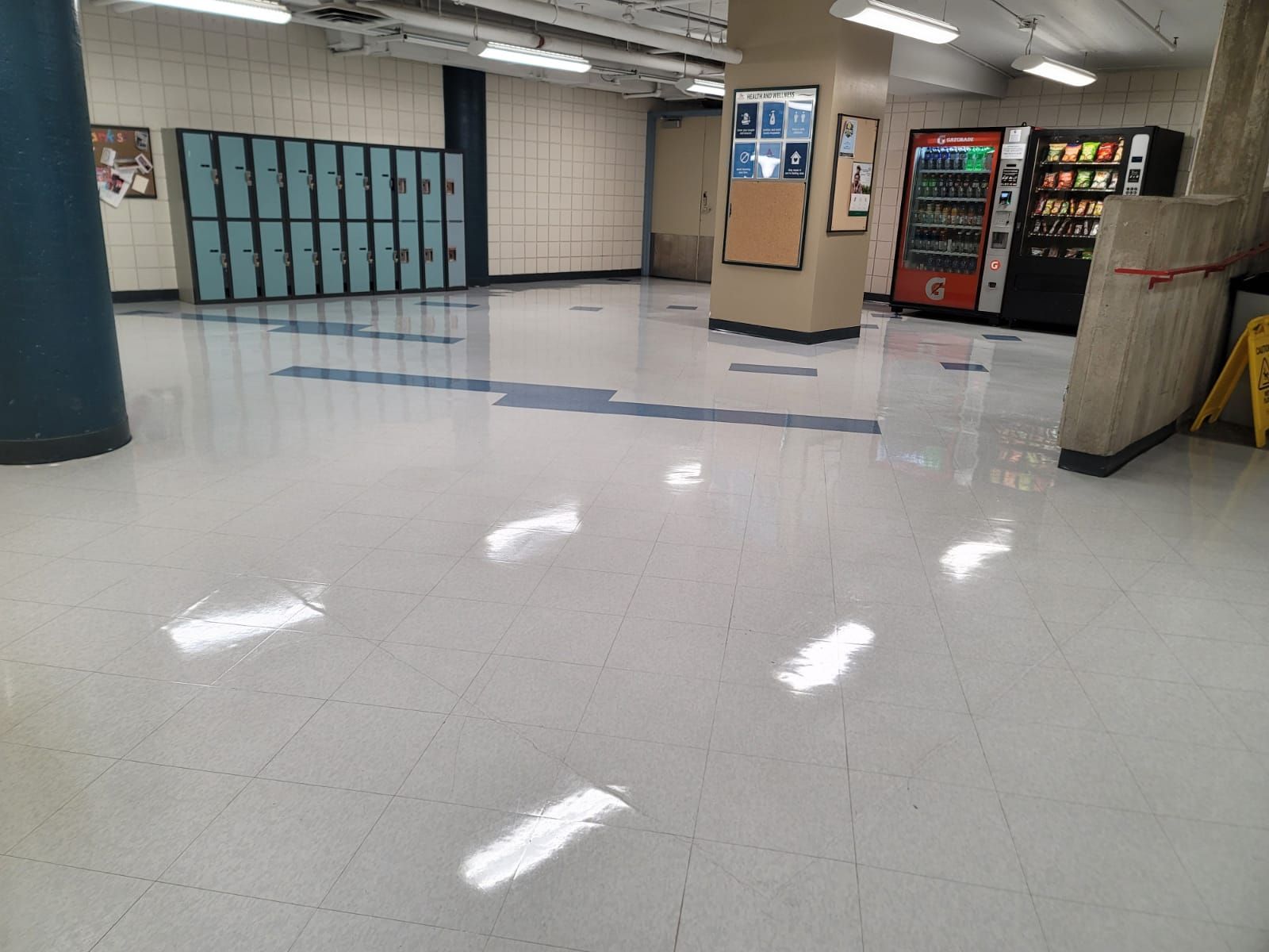 A large empty room with lockers and a vending machine.