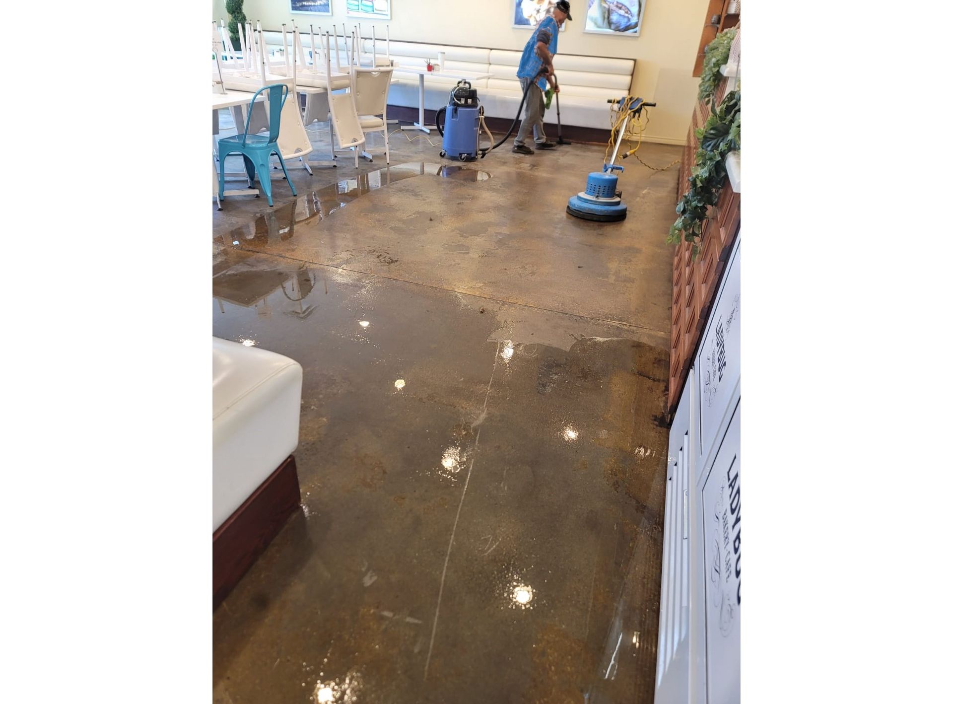 A man is cleaning the floor of a restaurant with a vacuum cleaner.