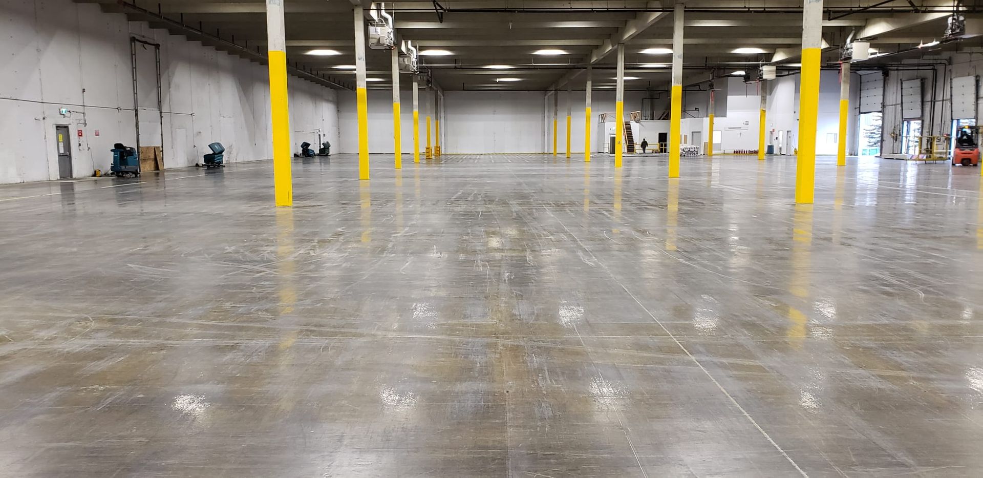 A large empty warehouse with concrete floors and yellow poles.