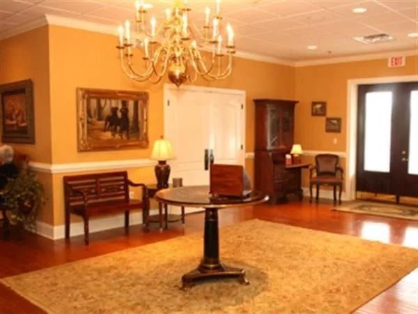 Elegant lobby with gold walls, wood furniture, and chandelier.
