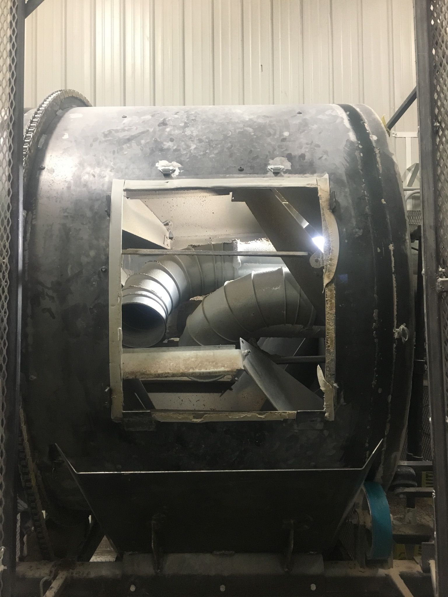A large black industrial metal drum with a square opening showing internal pipes and machinery.