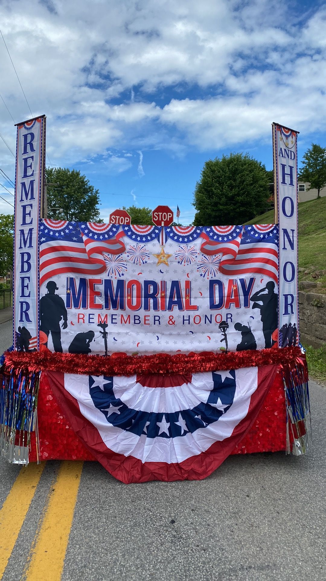 Memorial Day parade float with red, white, and blue bunting and signs reading “Remember” and “Honor”