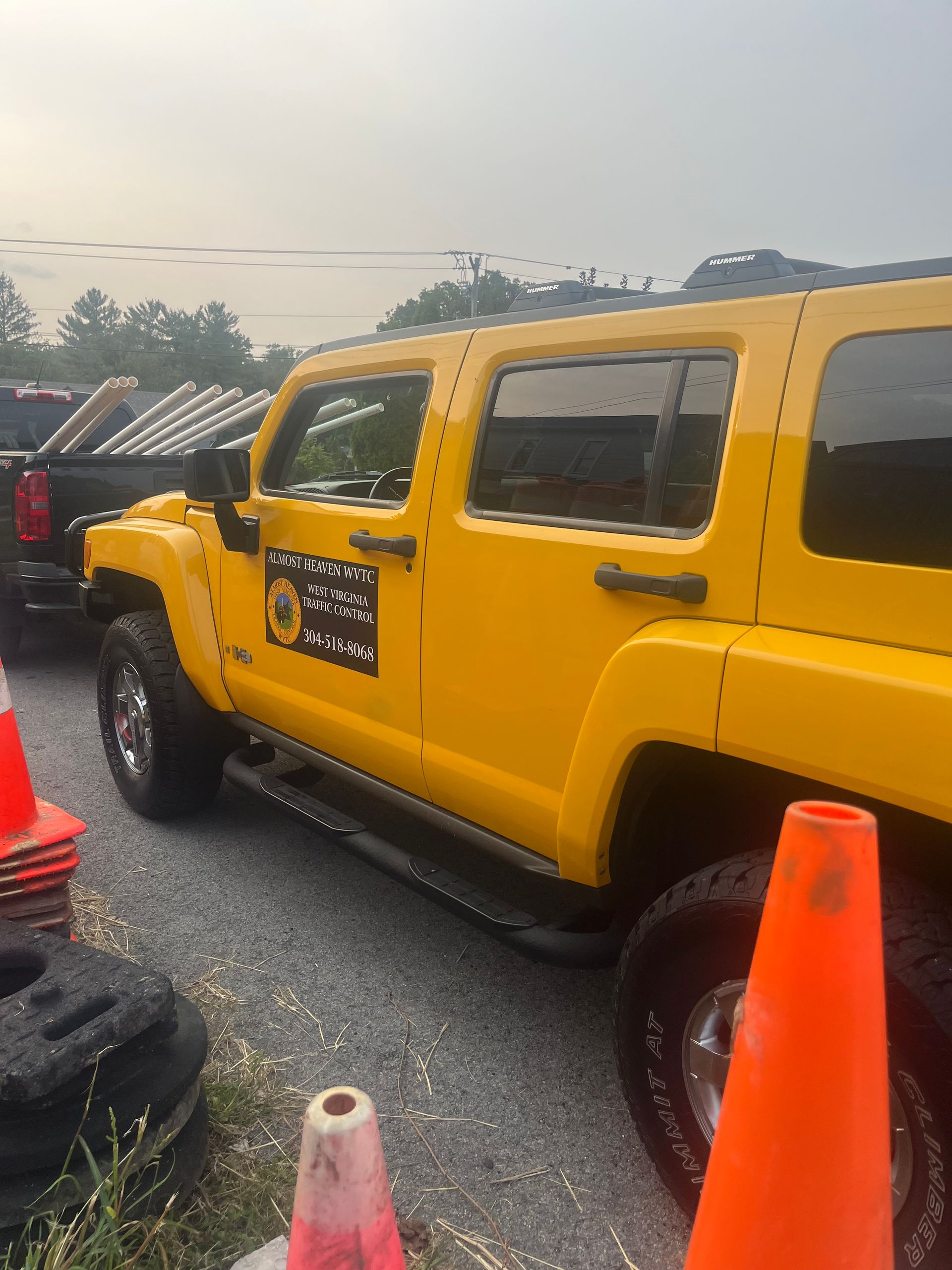 Yellow Jeep parked outdoors beside orange traffic cones.