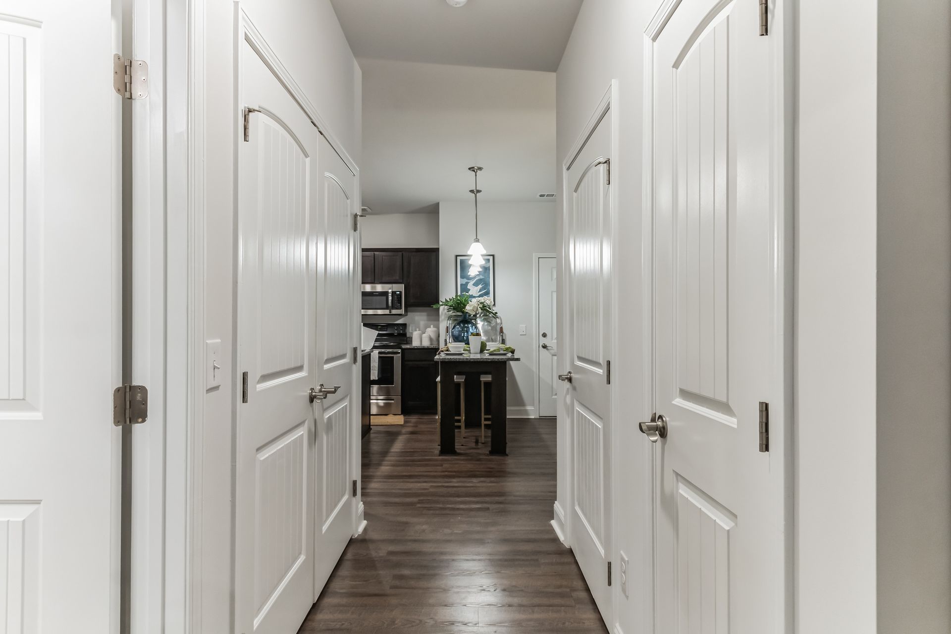 Hallway with coat closet, pantry, and laundry closet