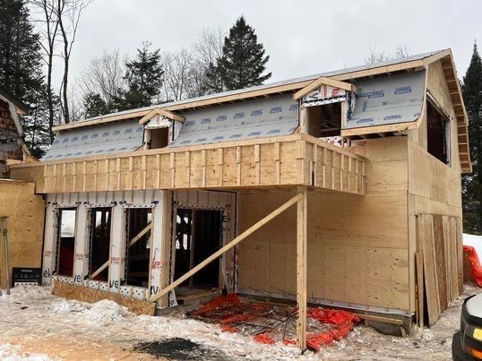 Bâtiment en construction, ossature bois, bardage partiel, neige au sol.