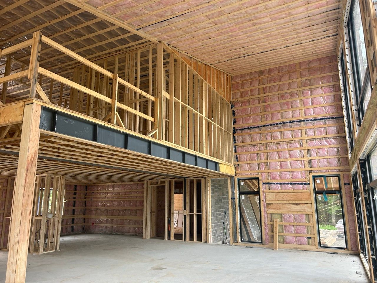 Intérieur d'un bâtiment en construction, montrant la charpente en bois, l'isolation et un étage.