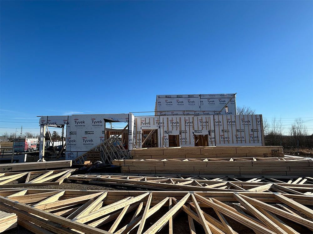 Bâtiment en construction par une journée ensoleillée, avec poutres en bois et ciel bleu.