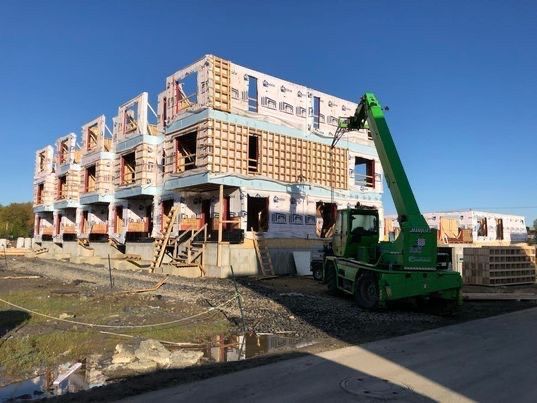 Chantier de construction : structure d'un bâtiment à plusieurs étages avec un chariot élévateur vert.