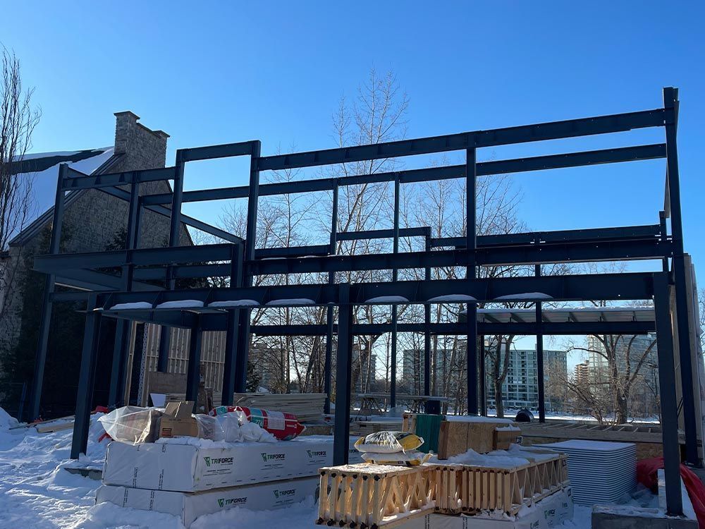 La charpente métallique d'un bâtiment en construction par temps de neige. Les matériaux de construction sont à la base.
