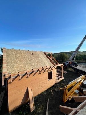 Bâtiment en bois en construction avec une grue par une journée ensoleillée.
