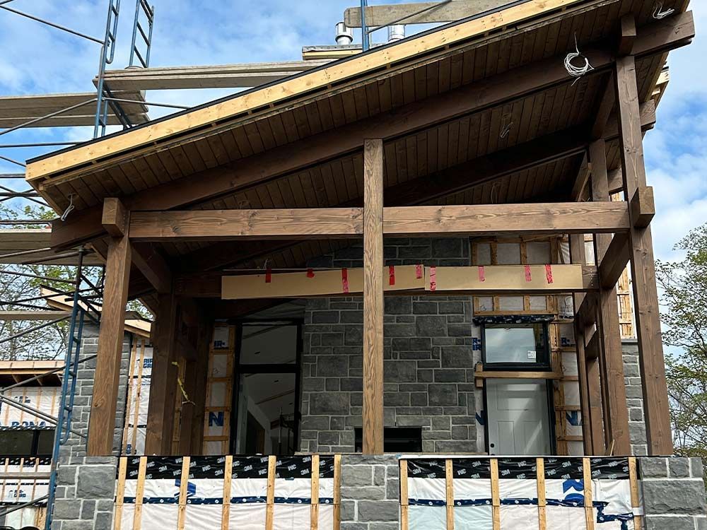 Construction d'un porche en bois avec mur en pierre, échafaudages et ciel.