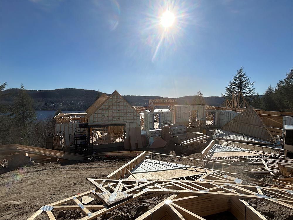 Chantier de construction avec charpente en bois se détachant sur un ciel bleu ensoleillé.