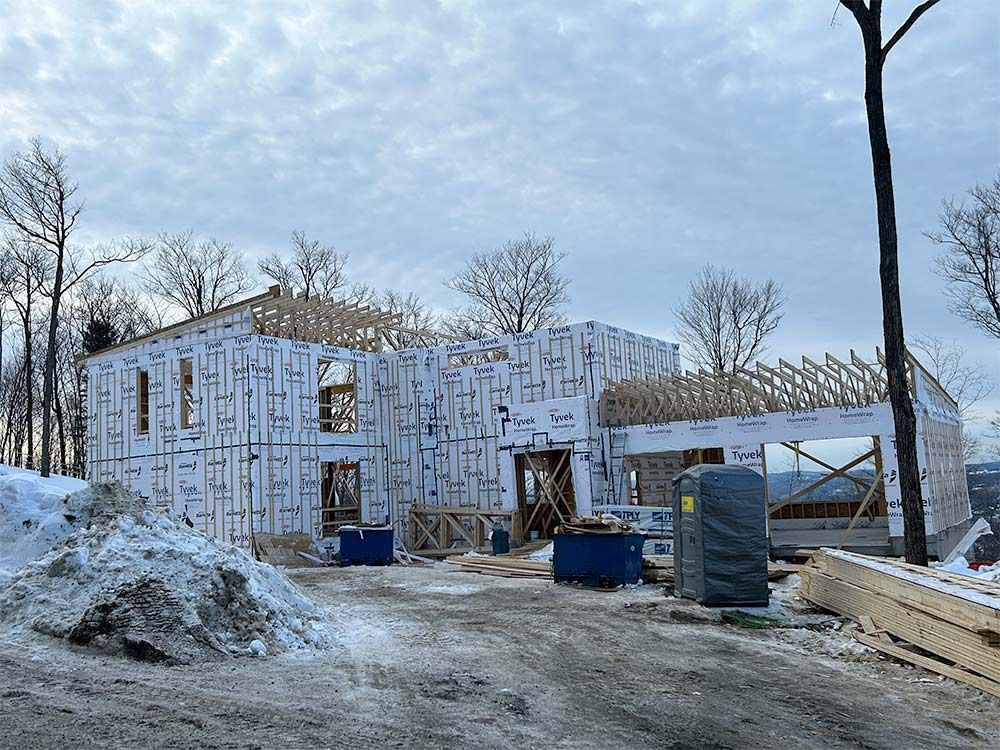 Construction d'une maison à deux étages avec ossature bois, bardage et toiture partiellement construite. Neige au sol.