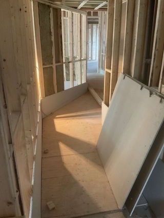 Travaux intérieurs, couloir inachevé avec ossature bois et cloisons sèches. Lumière naturelle.
