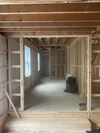 Ossature intérieure d'une pièce en construction avec portes, fenêtres et poutres apparentes.