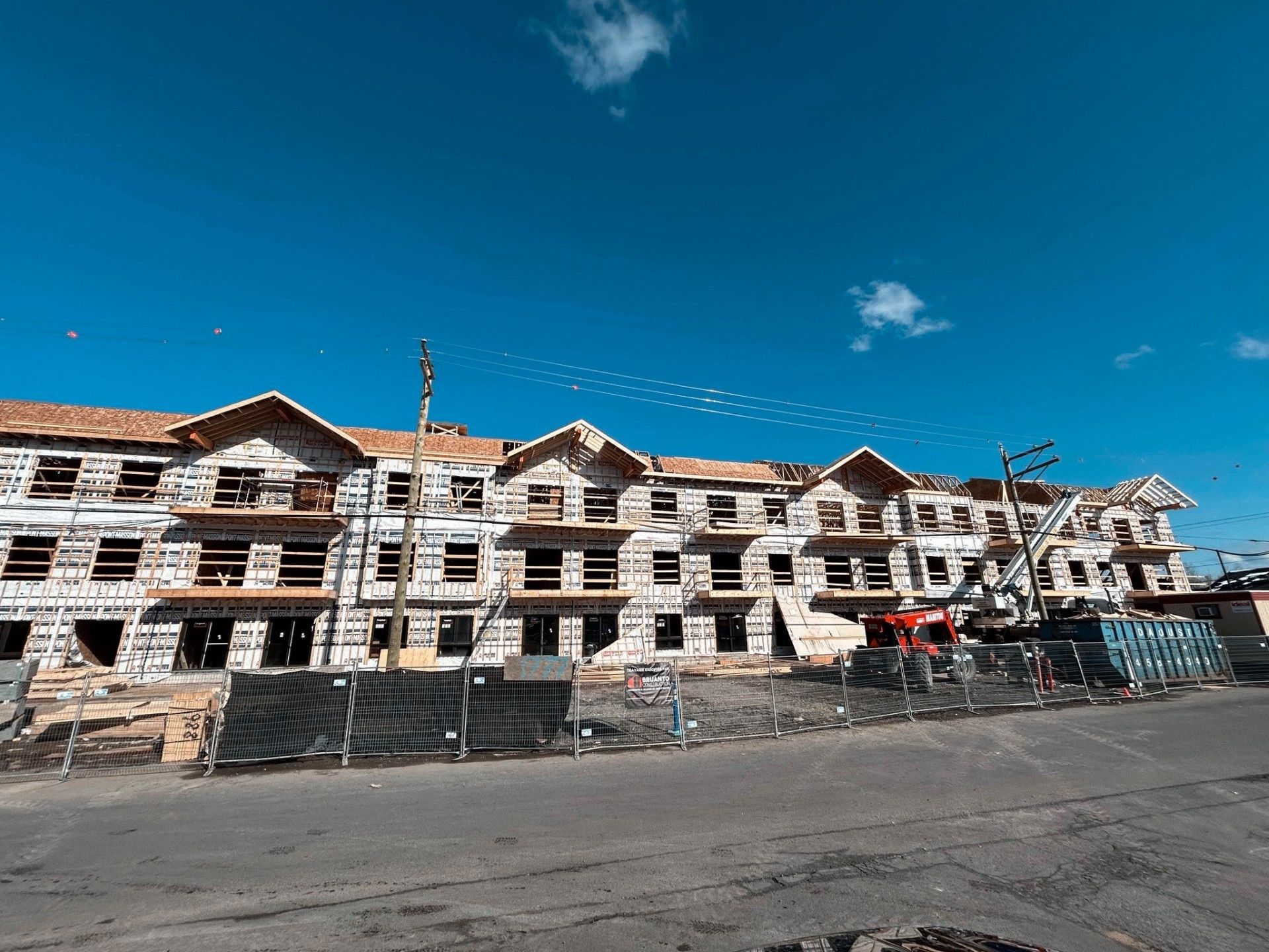 Immeuble à plusieurs étages en construction par une journée ensoleillée sous un ciel bleu.