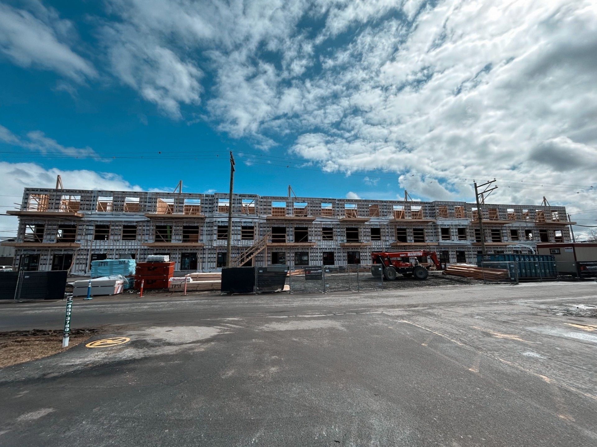 Chantier de construction d'un immeuble de plusieurs étages sous un ciel bleu nuageux.