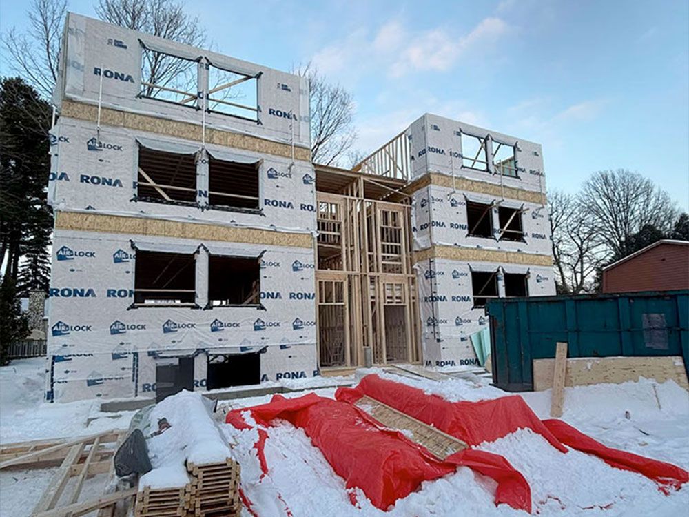 Bâtiment à ossature bois de plusieurs étages en construction, recouvert d'une bâche de protection, dans un décor enneigé.