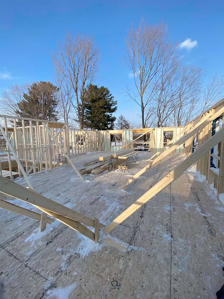 La charpente en bois d'un bâtiment en construction par une journée de neige.