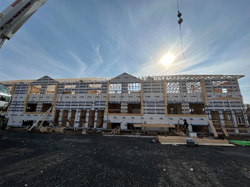 Bâtiment en construction avec ossature bois et revêtement bleu, journée ensoleillée.