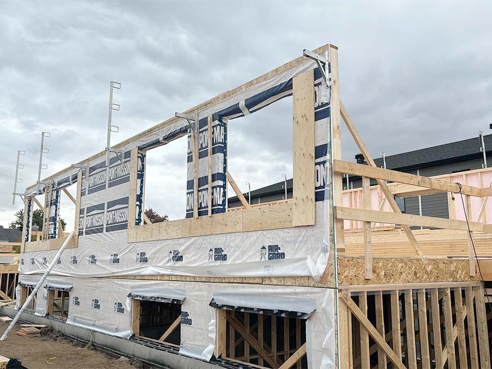 Ossature bois d'une maison en construction, avec fenêtres, par temps nuageux.