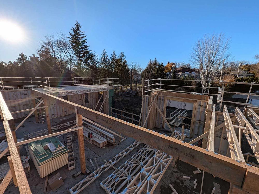 Chantier : charpentes en bois, fermes et échafaudages se détachant sur un ciel bleu azur.